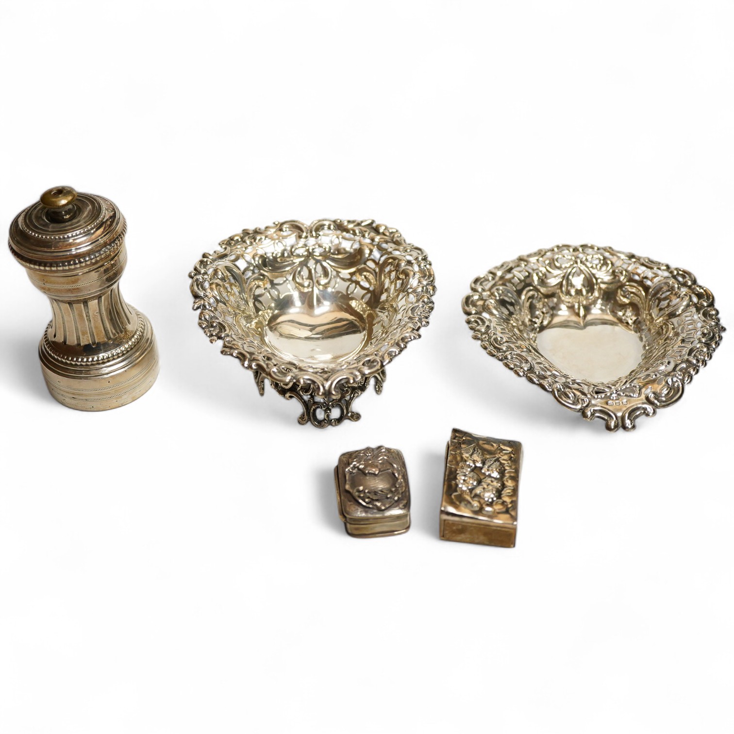 A collection of silver to include a late Victorian heart shaped pierced and embossed footed bonbon dish, London, 1901, William Comyns, another heart shaped bonbon dish, a French silver mounted pepper mill, a matchbox sle